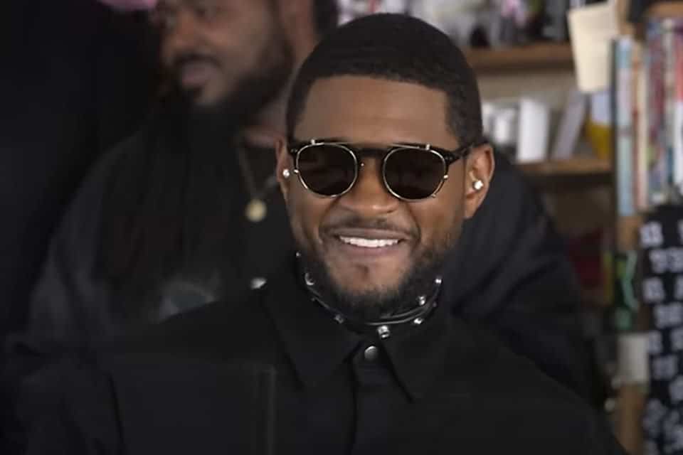 Foto colorida do cantor Usher. Ele está de óculos escuros e roupa preta. É um homem preto, de cabelo preto e curto - Metrópoles