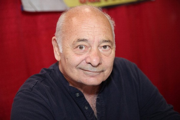 Foto colorida de Burt Young de camisa preta - Metrópoles