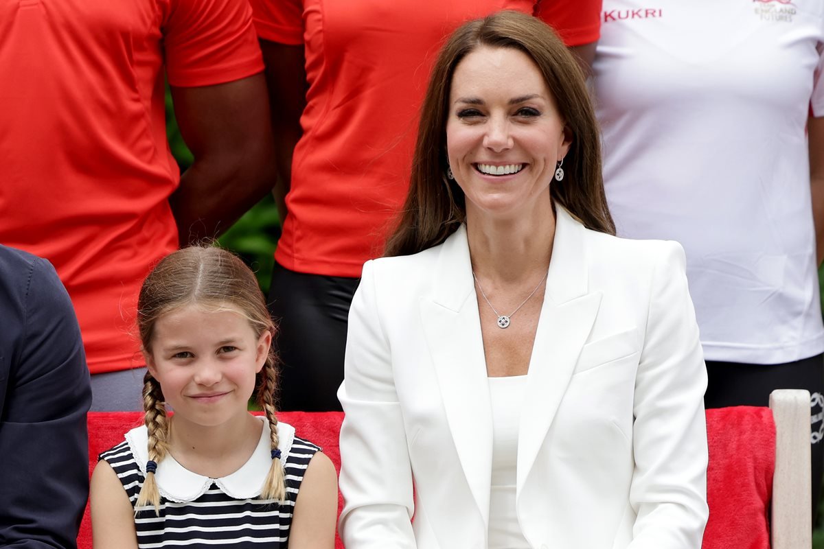 Foto de menina, branca, loira, de tranças, com vestido listrado, ao lado de mulher branca, com cabelo castanho e roupa branca - Metrópoles