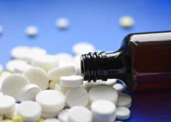 Round tablets arranged abstract isolated on blue color background. Pills for design. Concept of health, healthy lifestyle. Copy space for advertisement. Tablets are poured from a tube
