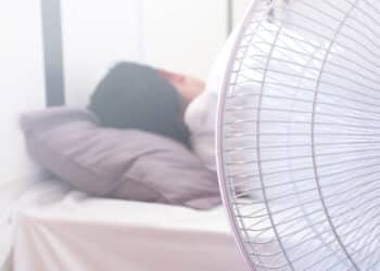 A man Sleeping on the bed and turn on the fan over the head risks of respiratory system.Health and medical care concepts