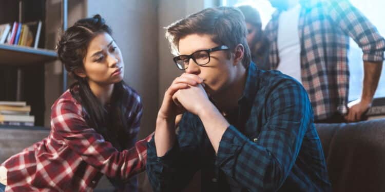 Young asian woman supporting male friend in depression, other people on background