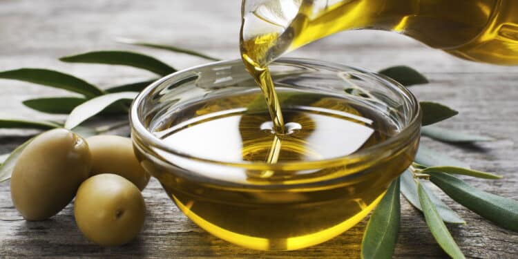 Bottle pouring virgin olive oil in a bowl close up