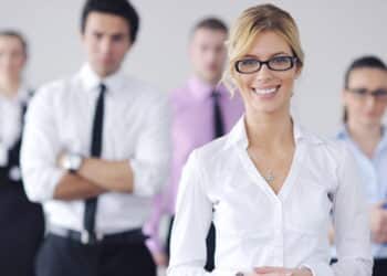 Successful business woman standing with her staff in background at modern bright office