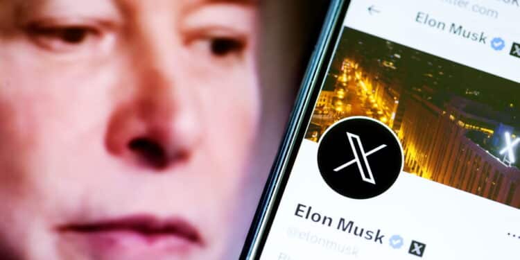 Elon Musks Twitter profile on a smartphone and Elon Musk in the background.