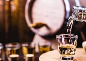 Glass of golden rum, with bottle. Bottle pouring alcohol into a small glass. Brazilian export type drink. Brazilian product for export, distilled drink known as brandy or pinga. Day of cachaça.