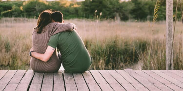 Couple in love embraced on their backs to reconcile and celebrate their love, sitting in nature.