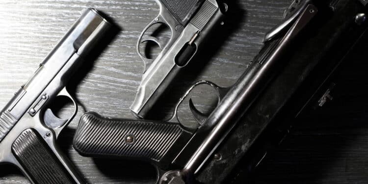 Terrorism concept. Handguns near submachine gun on dark wooden background under beam of light