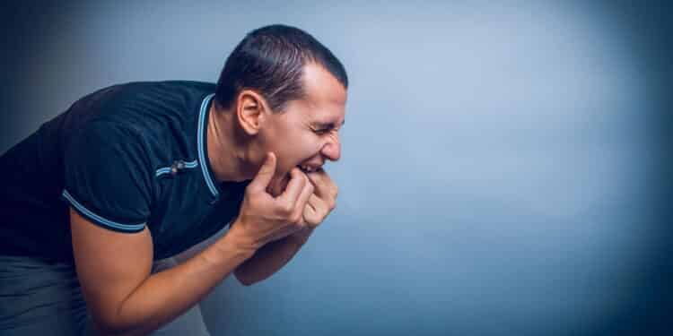 the man of European appearance brunet shoved his fingers in his mouth on a gray background cross process