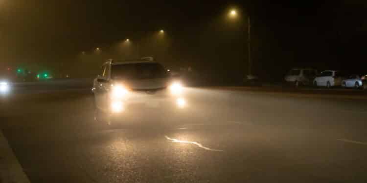 Road view of vehicles using the high beams in a foggy night