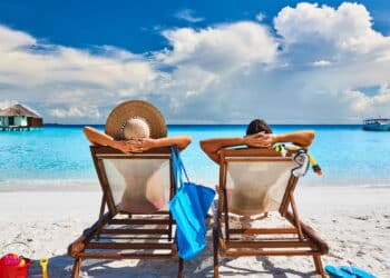 Couple in sun beds on a tropical beach at Maldives