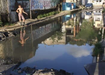 salvador, bahia, brazil - may 2, 2013: young man is seen near the accumulated sewage water on a street in the city of Salvador