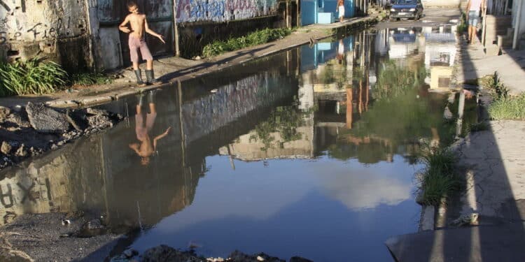 salvador, bahia, brazil - may 2, 2013: young man is seen near the accumulated sewage water on a street in the city of Salvador