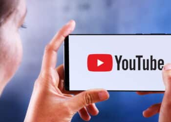 POZNAN, POL - JUL 10, 2019: Woman holding smartphone displaying logo of YouTube, an American video-sharing website headquartered in San Bruno, California. It operates as Google's subsidiaries