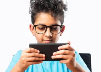 Indian asian small boy or kid using smartphone for gaming or for education