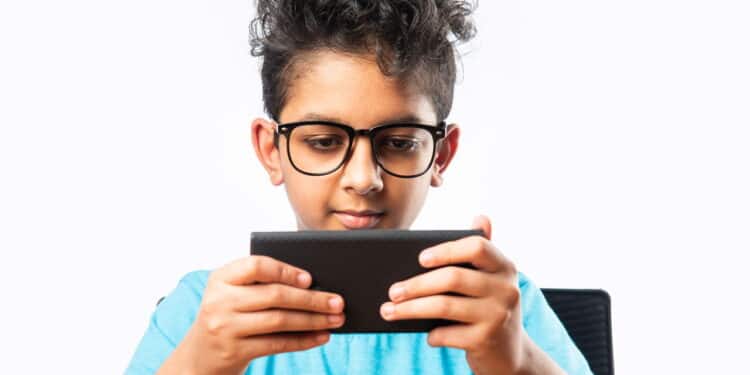 Indian asian small boy or kid using smartphone for gaming or for education