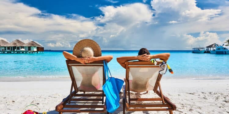 Couple in sun beds on a tropical beach at Maldives