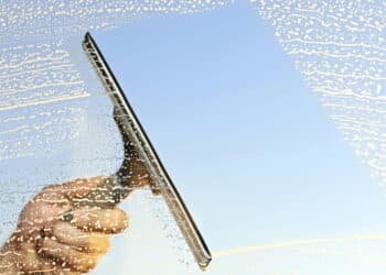 A hand and a squeegee cleaning windows