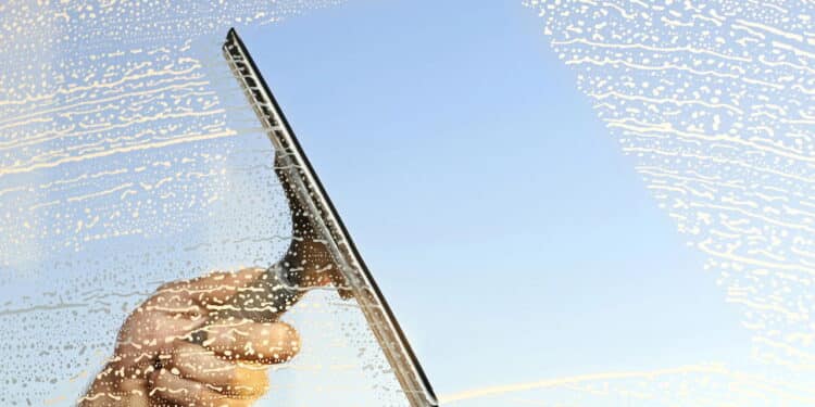 A hand and a squeegee cleaning windows