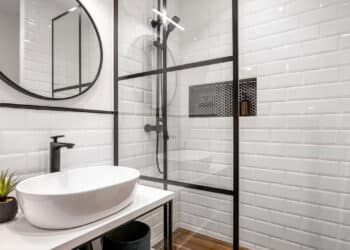 Simple bathroom with black shower, round mirror and classic white tiles.