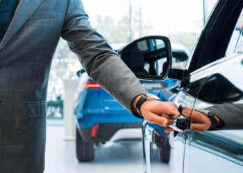 Homem abrindo porta do carro em concessionária - Créditos: depositphotos.com / VitalikRadko