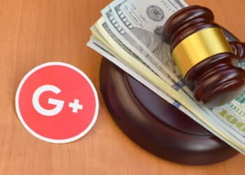 KHARKOV, UKRAINE - FEBRUARY 17, 2020: Google plus paper logo lies with judge gavel and hundred dollar bills. Entertainment lawsuit concept