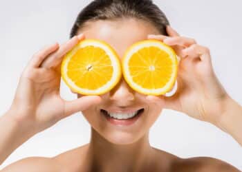 Imagem de mulher cobrindo os olhos com fatias de laranja - Créditos: depositphotos.com / VitalikRadko