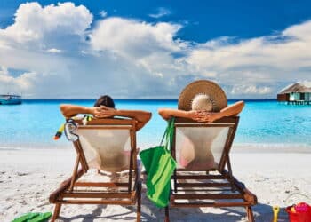 Couple in sun beds on a tropical beach at Maldives