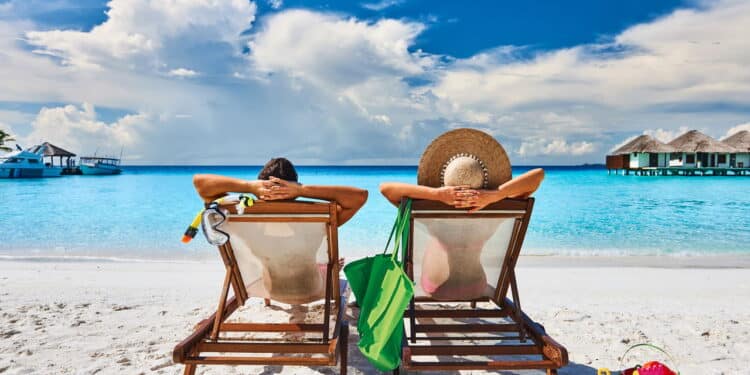 Couple in sun beds on a tropical beach at Maldives