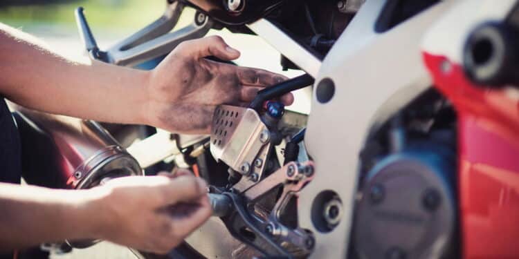 Imagem de homem trocando peça de moto - Créditos: depositphotos.com / dmvasilenko