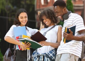 After Exam. Cheerful international students celebrating successful test pass, standing near university building