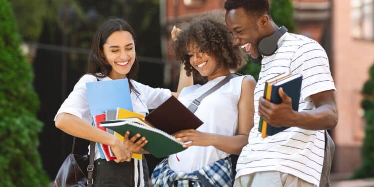 After Exam. Cheerful international students celebrating successful test pass, standing near university building