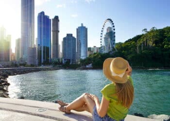 Holidays in Brazil. Attractive young woman enjoying sunset sitting on promenade in Balneario Camboriu, Santa Catarina, Brazil.