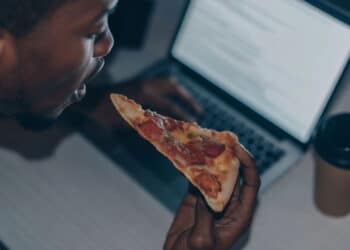 Imagem de homem comendo pizza de noite - Créditos: depositphotos.com / AndrewLozovyi