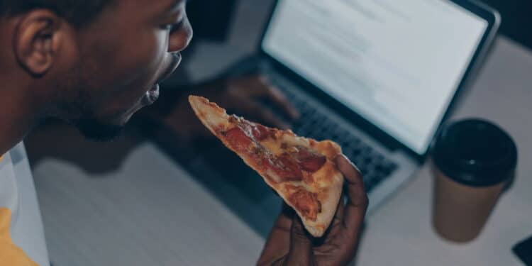 Imagem de homem comendo pizza de noite - Créditos: depositphotos.com / AndrewLozovyi