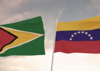 SPECTACULAR FLAGS OF GUYANA AND VENEZUELA WAVING WITH A BLUE SKY BACKGROUND CONFLICT RELTATIONSHIPS