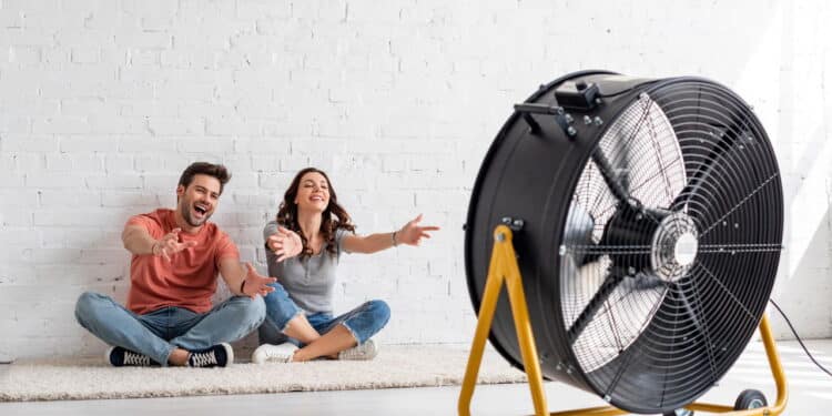 Casal sentado em frente ao ventilador elétrico - Créditos: depositphotos.com / HayDmitriy