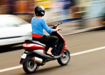 Imagem de moto andando entre carros - Créditos: depositphotos.com / akarelias