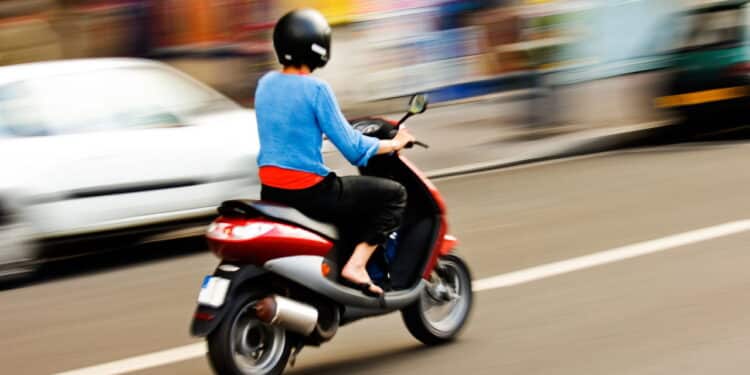 Imagem de moto andando entre carros - Créditos: depositphotos.com / akarelias