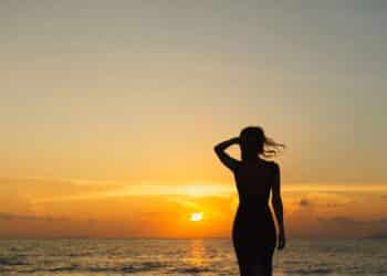 Mulher vendo Por do Sol na praia - Créditos: depositphotos.com / YuliyaKirayonakBO