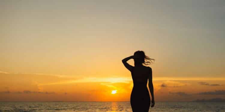 Mulher vendo Por do Sol na praia - Créditos: depositphotos.com / YuliyaKirayonakBO