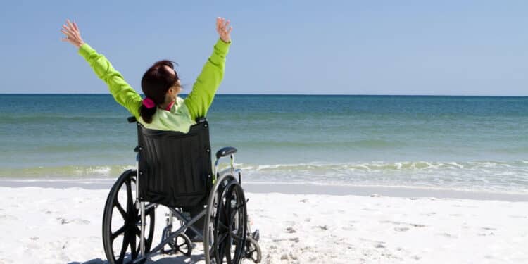 Imagem de mulher cadeirante na praia - Créditos: depositphotos.com / sframe