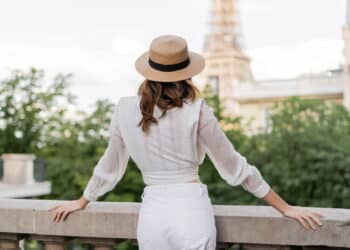 vista de turista com chapéu de sol em pé com a Torre Eiffel desfocada ao fundo em Paris