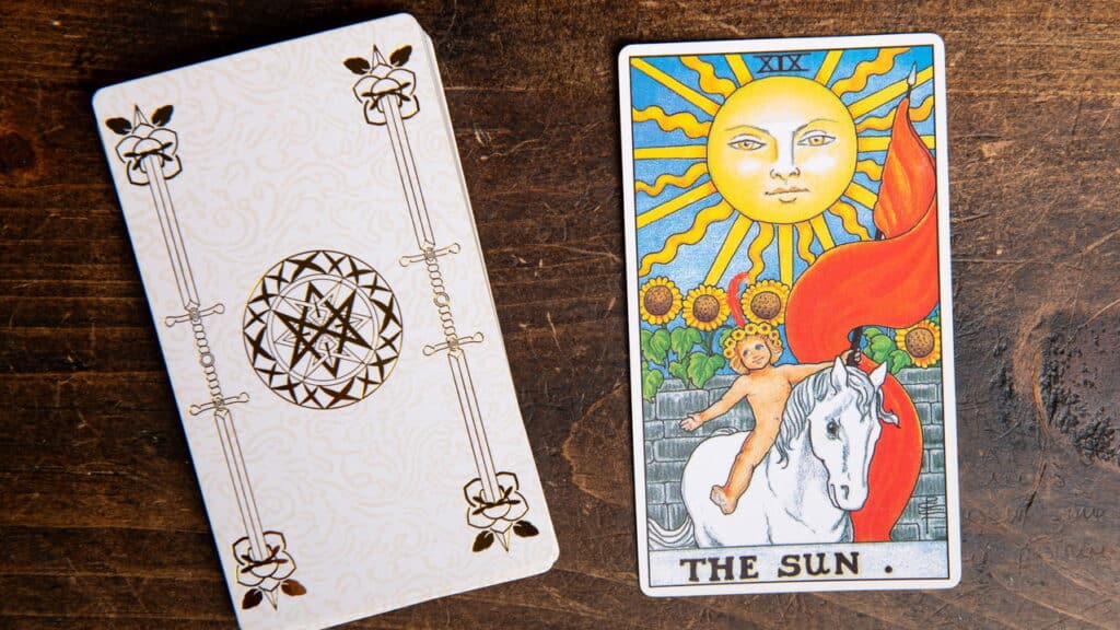 Carta de Tarô do Sol do baralho Rider Waite sobre fundo de madeira