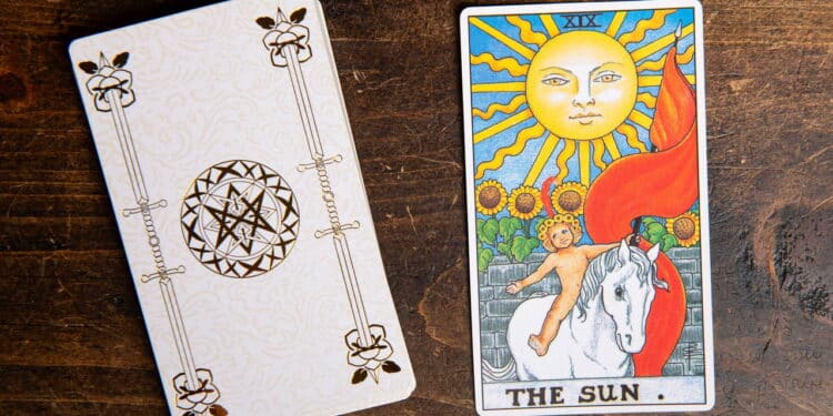 Carta de Tarô do Sol do baralho Rider Waite sobre fundo de madeira