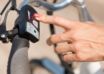 Mulher ligando a bicicleta elétrica - Créditos: depositphotos.com / microgen