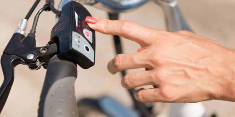 Mulher ligando a bicicleta elétrica - Créditos: depositphotos.com / microgen