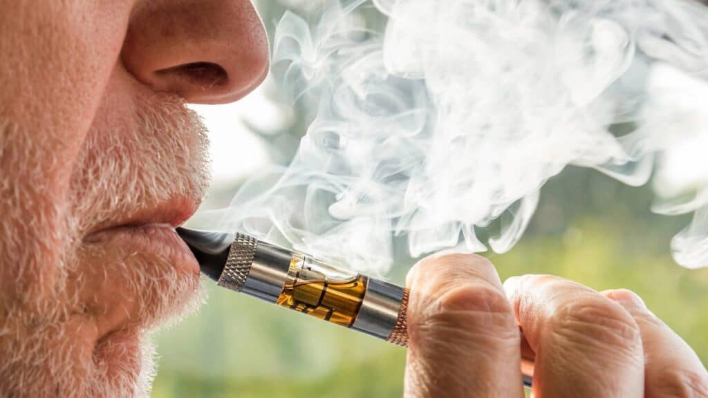 Homem idoso adulto fumando um cigarro eletrônico Créditos: depositphotos.com / elesi