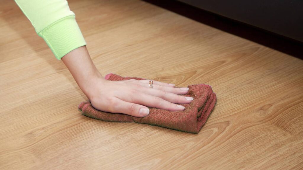 Mão de mulher limpando o chão com um pano.