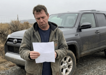 Homem decepcionado com folha em mãos ao lado do seu SUV